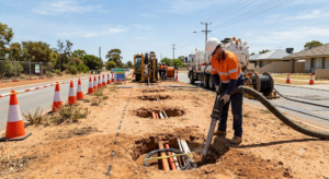 Vacuum Excavation for NBN and Telecom Projects in WA Operator potholing along a roadside with a vacuum hose to safely expose buried NBN cables and conduit in Western Australia.